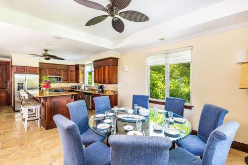 a dining room with a glass table and blue chairs at Villa La Percha in Providenciales