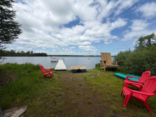 a group of chairs sitting on the grass near a lake at Sandy Cove in Saint Germain