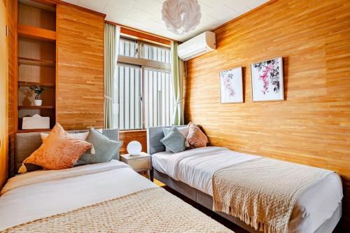 two beds in a room with wood paneled walls at Rela More in Ginowan