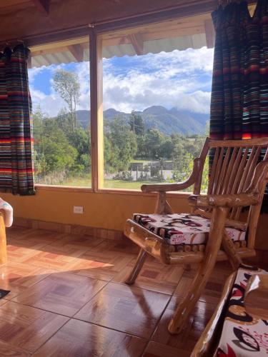 a rocking chair in a room with a large window at Refugio del venado Cuicocha in Cotacachi