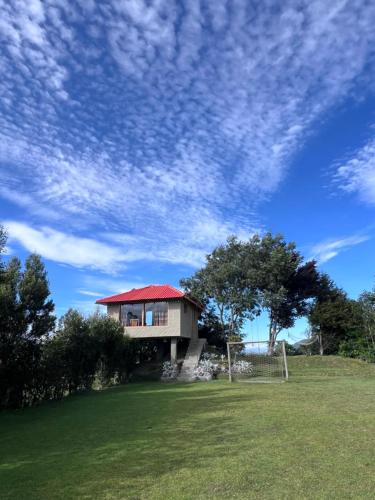 a house with a red roof on a grass field at Refugio del venado Cuicocha in Cotacachi