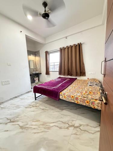 a bedroom with a bed with purple sheets and a window at Gurukrupa Yatri Nivas in Kolhapur