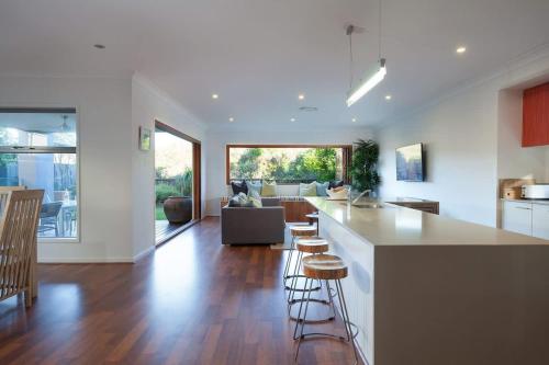 a kitchen and living room with a counter and chairs at Green House in Marcoola