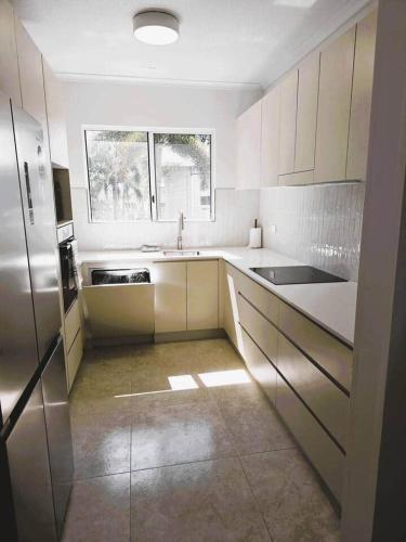 a large kitchen with white cabinets and a window at Apartment on The Strand - 2 Bed 2 Bath in North Ward