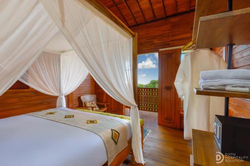 a bedroom with a bed with a canopy at Umah Dedari in Keramas