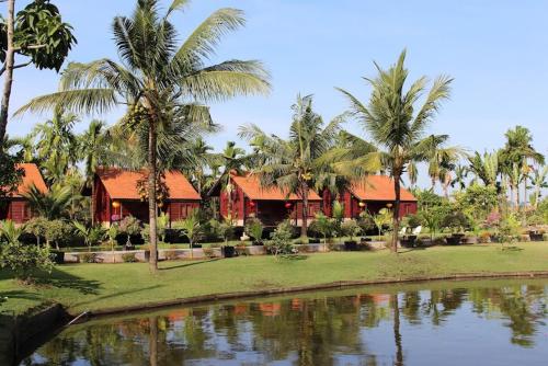 a resort with palm trees and a body of water at Woods House Homestay in Sa Ðéc