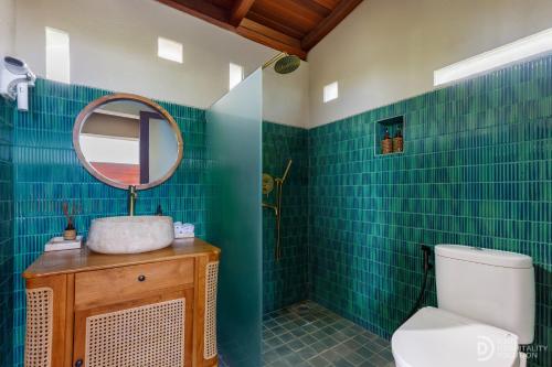 a bathroom with a toilet and a mirror at Umah Dedari in Keramas