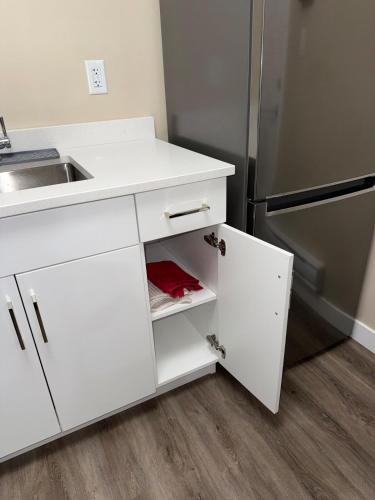 a white kitchen with a sink and a refrigerator at Modern Private Suite, Cozy, Stylish & Spacious in Regina