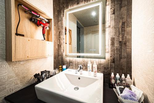 a bathroom with a white sink and a mirror at Hotel M in Oyodo