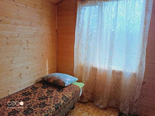 a bedroom with a bed with a curtain and a window at Коттедж Бурабай улица Алатау 38 in Borovoye