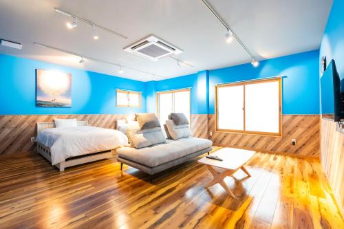 a bedroom with blue walls and a bed and a couch at Hotel Beach-House in Otsu