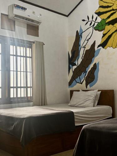 a bedroom with a bed with a painting on the wall at Zzz Ijen Hostel in Banyuwangi