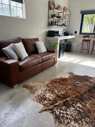 a living room with a brown leather couch and a rug at Market on 5 in Piet Retief