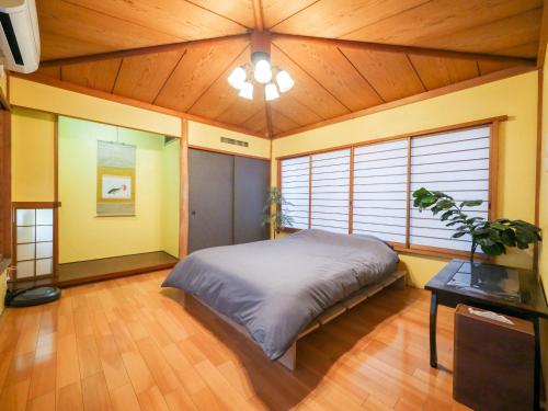 ein Schlafzimmer mit einem großen Bett in einem Zimmer mit Holzdecke in der Unterkunft E E House in Numazu