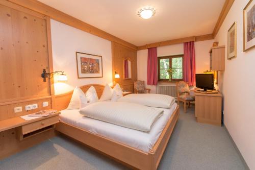 a bedroom with a bed and a desk and a television at Der Erlhof Restaurant & Landhotel in Zell am See