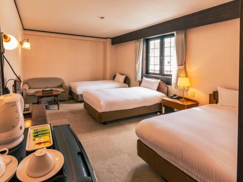 a hotel room with two beds and a desk at Shakespeare Hotel in Hakuba