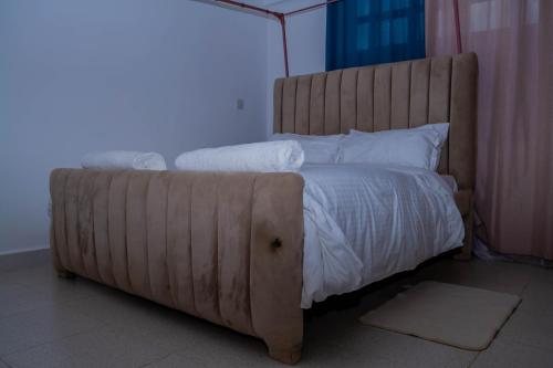 a large bed with a wooden headboard in a room at M's BNB in Bungoma