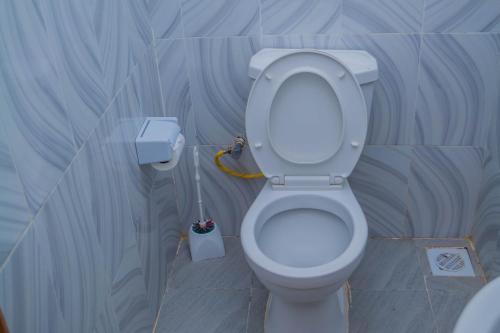 a bathroom with a toilet with a cleaning brush at M's BNB in Bungoma