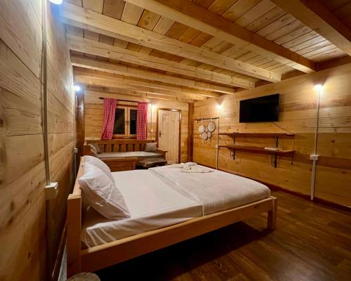 a bedroom with a bed in a wooden cabin at Lagano Mountain Retreat - Via Ferrata & Restaurant in Gusinje