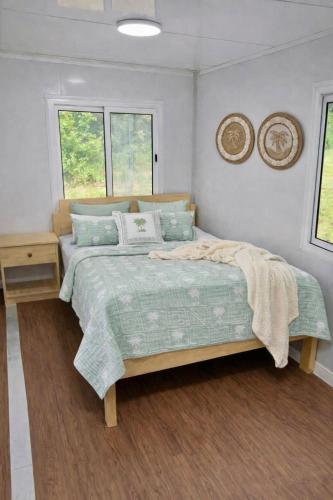 a bedroom with a bed and a table and two windows at Aore Shores Beachfront Bungalow in Aore Island