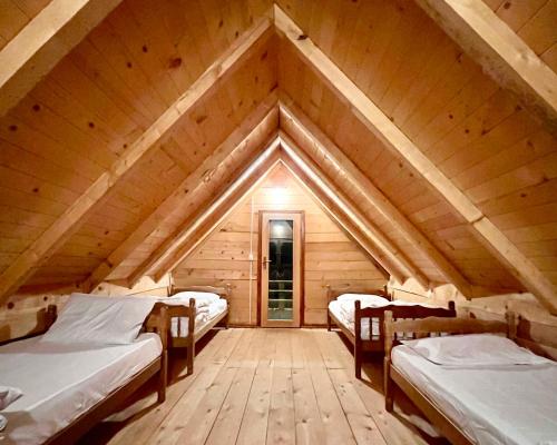 a room with three beds in a wooden attic at Lagano Mountain Retreat - Via Ferrata & Restaurant in Gusinje