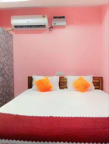 a bedroom with a bed with orange and white pillows at BHS Deluxe Rooms in Puri