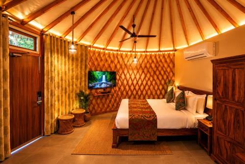 a bedroom with a bed and a tv in a room at Bel-La Monde Riverside Jim Corbett - "A Unit of Luxe Opera Hotels & Resorts" in Garjia