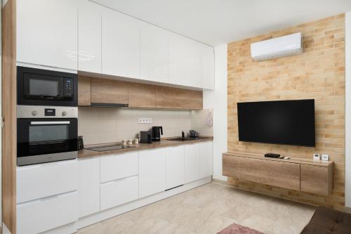 a kitchen with white cabinets and a flat screen tv at DowntownKate in Debrecen