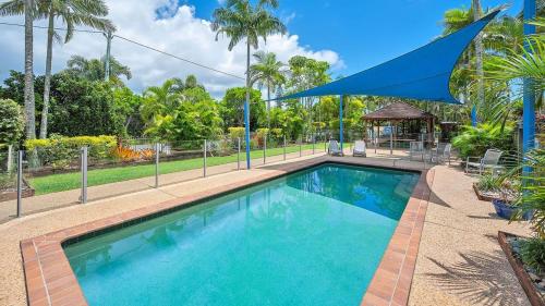 a large swimming pool with a blue umbrella over it at Tripcony Quays Unit 11 in Caloundra
