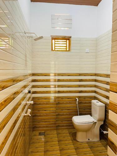 a bathroom with a toilet and wooden walls at Lotus Green Hotel And Restaurant in Arugam Bay