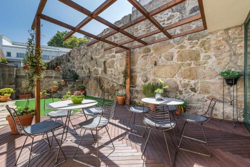 a patio with tables and chairs and a stone wall at GuestReady - Jardim das Oliveiras GuestHouse in Porto