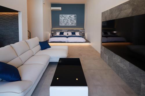 a living room with a white couch and two beds at Mare Blu Amami in Tatsugo