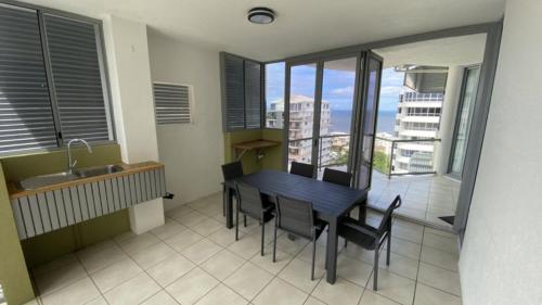 a kitchen with a table and chairs and a balcony at The Pinnacles Caloundra Unit 92 in Caloundra