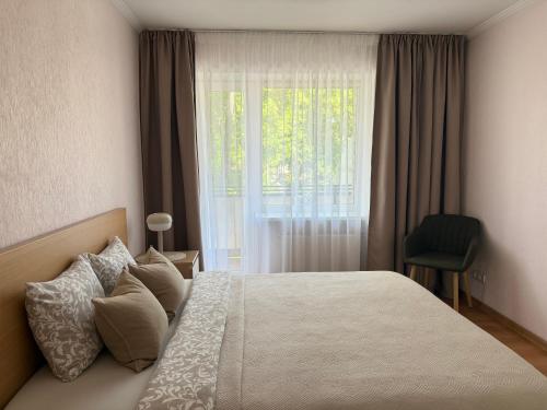 a bedroom with a bed with a window and a chair at Center two bedroom apartment in Daugavpils