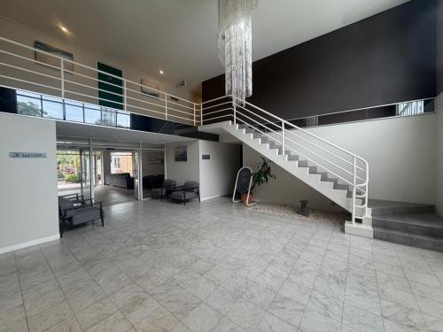 a large lobby with a staircase in a building at Seaside Garden Hotel in Wamberal