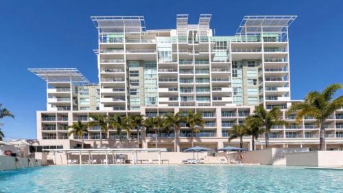 a hotel with a swimming pool in front of a building at Lovely Studio Apartment Overlooking Golf Course! in Pelican Waters