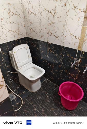 a bathroom with a toilet and a pink bucket at ROYAL budget Rooms in Ooty
