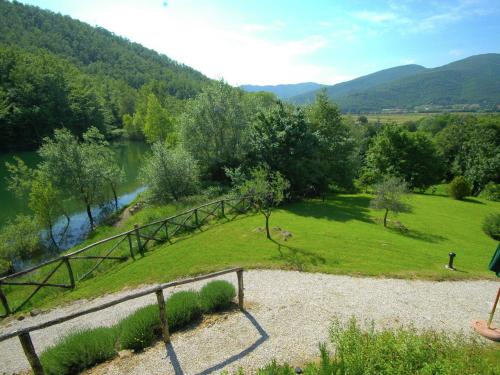 a woman standing next to a fence next to a river at Cottage in Umbria with pool in Casella
