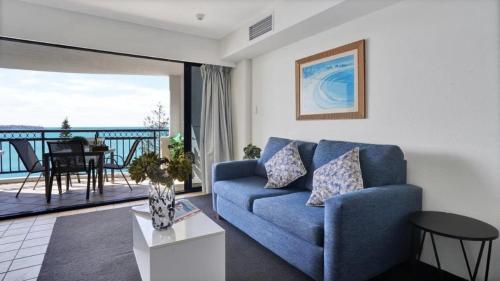 a living room with a blue couch and a balcony at #812 Ramada Resort, Beachfront in Golden Beach