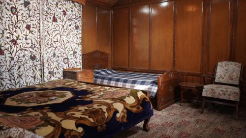 a bedroom with two beds and a chair at Houseboat Saleem in Dal Lake