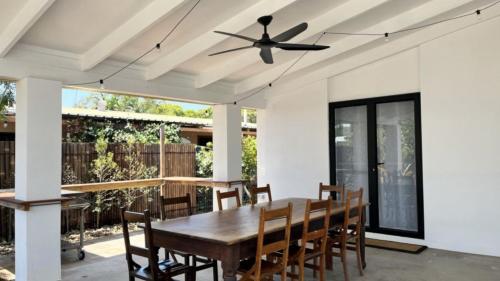 a dining room with a ceiling fan and a wooden table at Beachside Bliss In The Crown in Kawana Waters