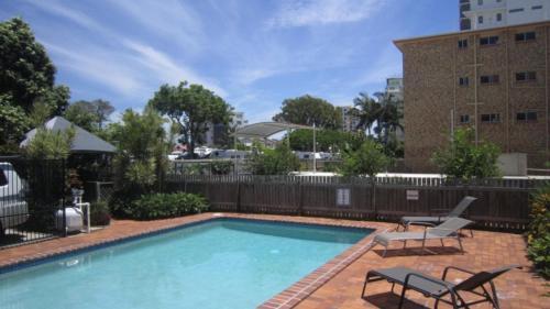 a swimming pool with two chairs and a building at Windbourne Unit 8 in Golden Beach
