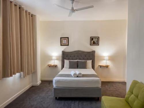 a bedroom with a bed and a green chair at hotel barmel in Siguatepeque
