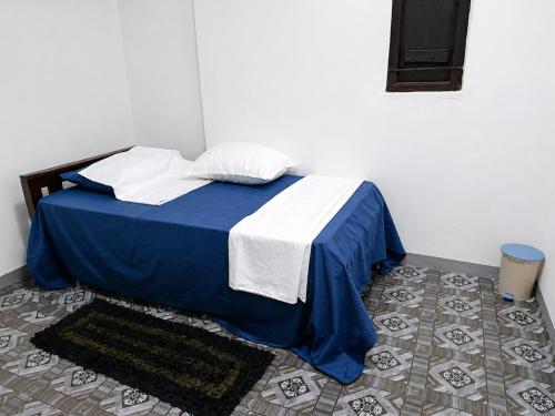 a bedroom with a bed with a blue and white blanket at A to Z surf camp in Arugam Bay