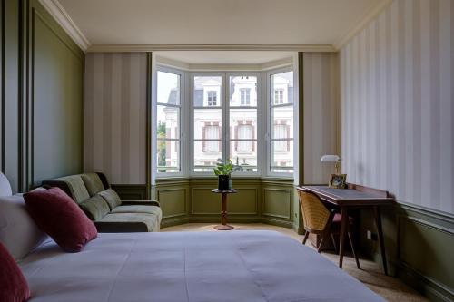 a bedroom with a bed and a couch and windows at Villa Henriette in Cabourg