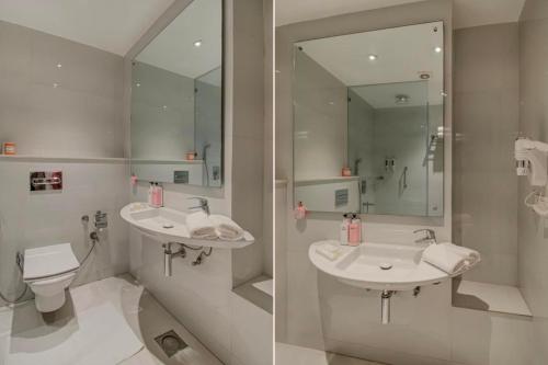 a bathroom with two sinks and a toilet and a mirror at Iris Park Hotel New Delhi in New Delhi