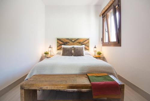 a bedroom with a large bed and a wooden bench at Casa Poniente, encantadora casa de 2 dormitorios con jardín in Zahora