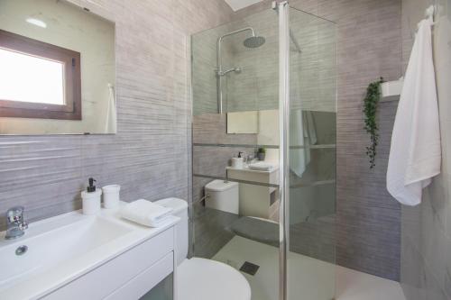 a bathroom with a shower and a toilet and a sink at Casa Poniente, encantadora casa de 2 dormitorios con jardín in Zahora