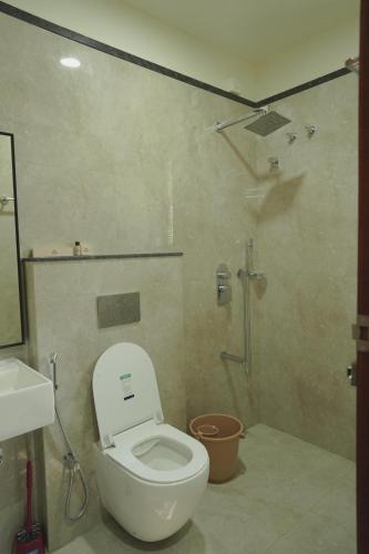 a bathroom with a white toilet and a shower at Ezzora Stays in Kozhikode