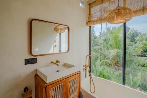 a bathroom with a sink and a tub and a window at Santara Villa Ubud in Ubud